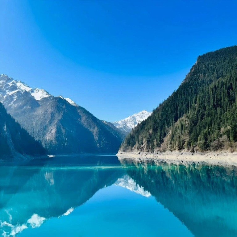 Blue lake with distant snow mountains in Jiuzhaigou Valley, China