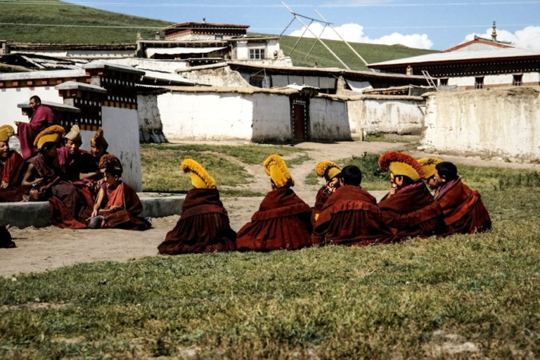 Monks in traditional Tibetan attire gathering outdoors at a monastery in China.