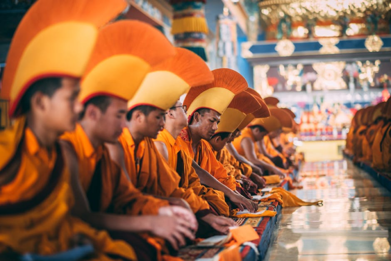 Tibetan monks in traditional attire praying inside a colorful temple, embracing culture and spirituality.