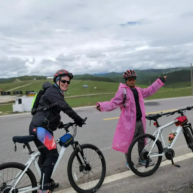 A traveler and guide standing with bicycles on an open road in Western Sichuan