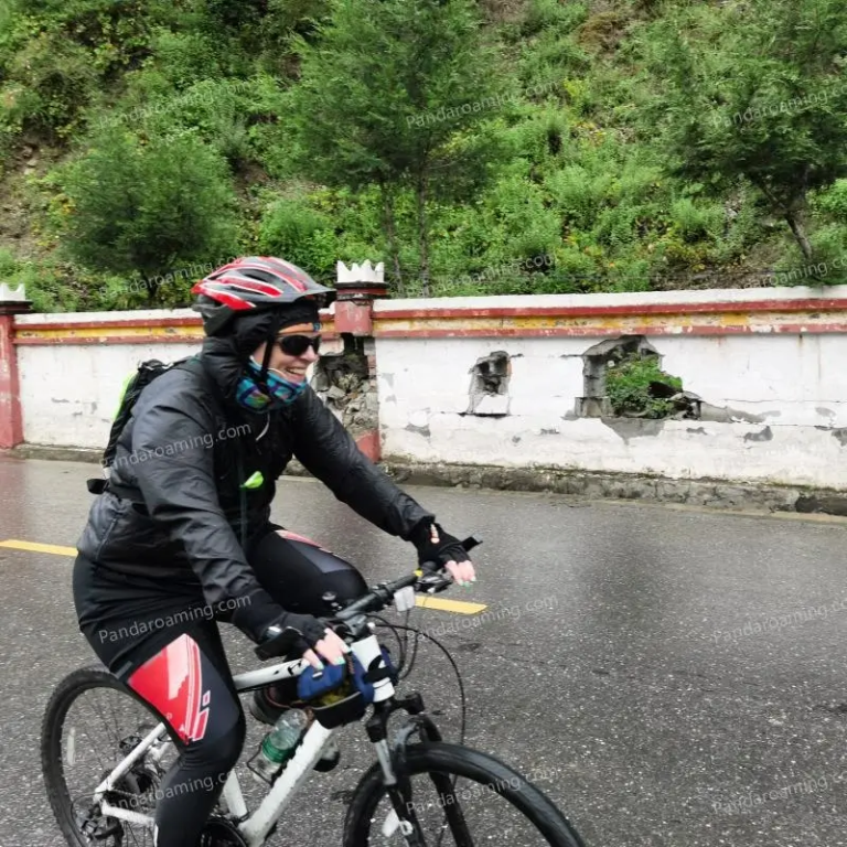 A traveler smiling while cycling on a mountain road in Western Sichuan
