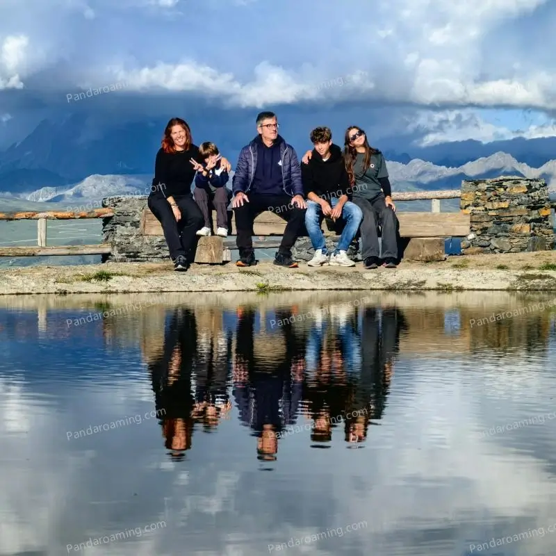 A family of five sitting by a lake with mountain reflections during a Western Sichuan trip
