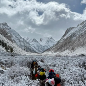 Trekking group hiking through the snow mountain landscapes of Qizanggou Valley