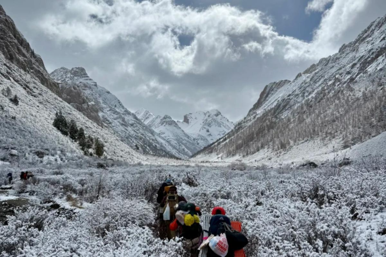 Trekking group hiking through the snow mountain landscapes of Qizanggou Valley