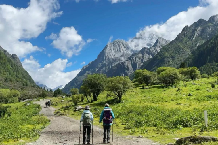 Two hikers walking through Changpinggou Valley at Siguniang Mountain