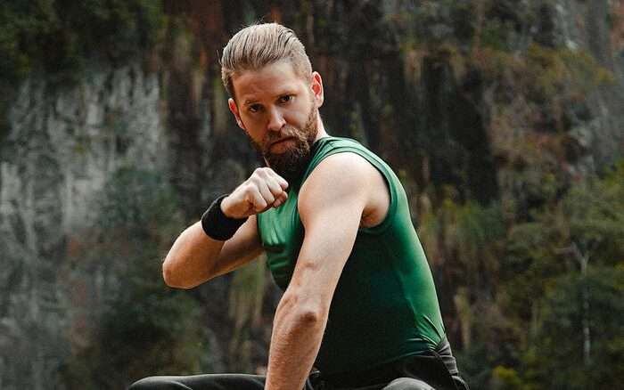 Young man practicing martial arts outdoors in nature.