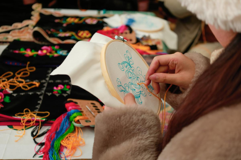 Traveler learning traditional handicraft sewing in Zhonglu Tibetan Village